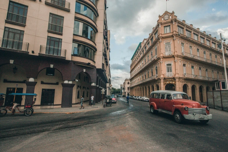 a red car driving down a street next to tall buildings, a photo, pexels contest winner, colonial style, cuban setting, faded and dusty, hd wallpaper