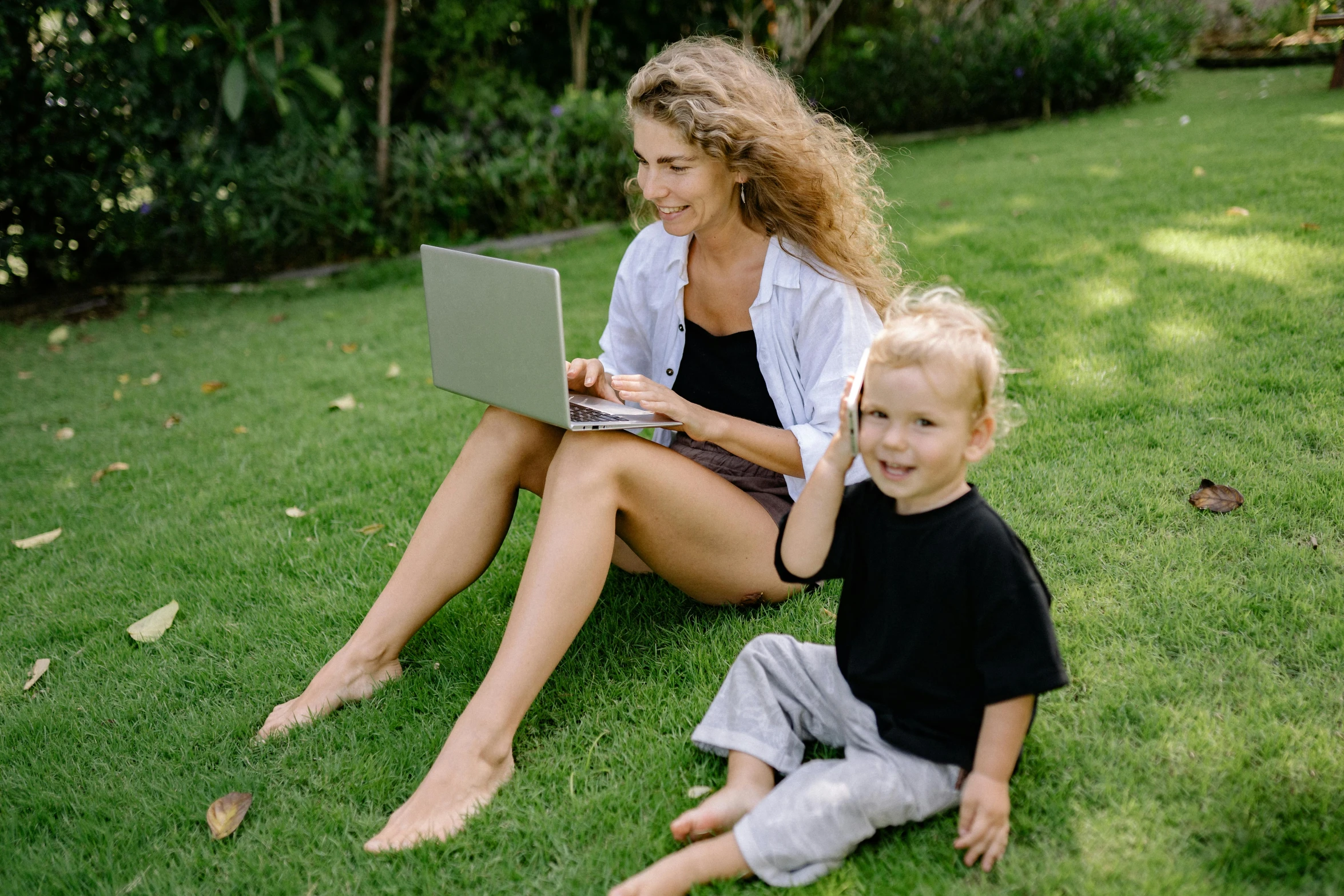 a woman and a child sitting on the grass with a laptop, by Carey Morris, pexels, avatar image, lush lawn, a blond, people at work