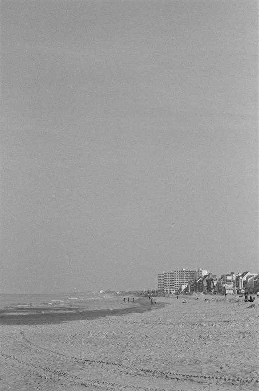 a black and white photo of a beach, by Maurycy Gottlieb, 2 5 6 x 2 5 6, buildings in the distance, color image, ( ( photograph ) )