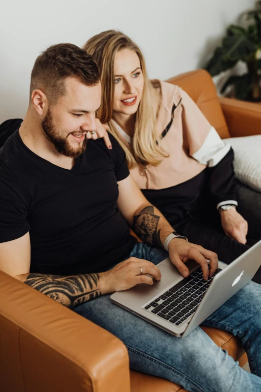 a man and woman sitting on a couch with a laptop, trending on pexels, tattooed, tuomas korpi and wlop, german, casey cooke