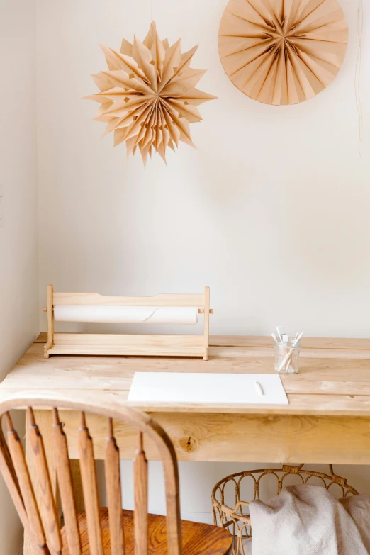 a wood table with chairs and a table that has a paper pinwheels hanging above it