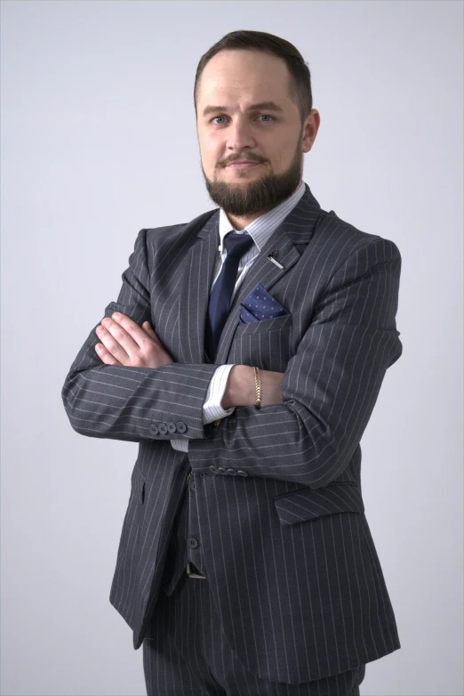 a man in a suit standing with his arms crossed, inspired by Agnolo Gaddi, pexels contest winner, hurufiyya, frontal pose, bearded, low quality photo, full color photograph