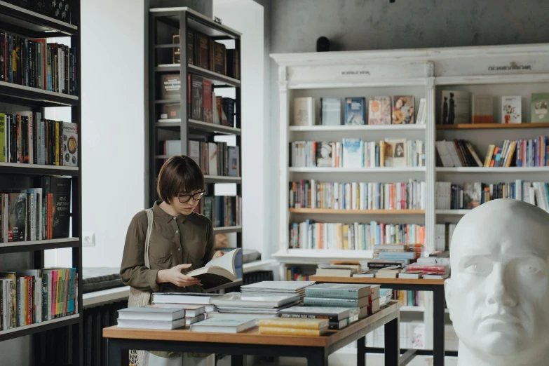 a woman is reading a book in a library, pexels contest winner, on a white table, inspect in inventory image, gif, non-binary