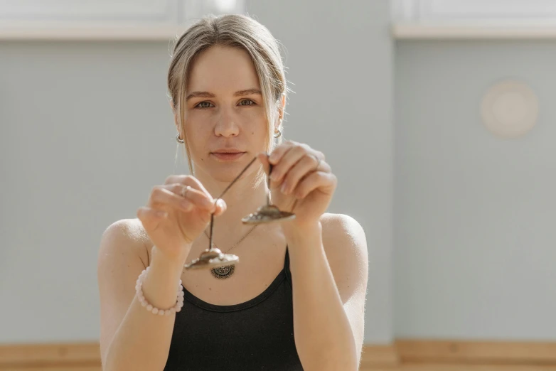 a woman holding a wine glass in front of her face, inspired by Anna Füssli, kinetic art, spoon placed, silver jewellery, yoga, low quality photo