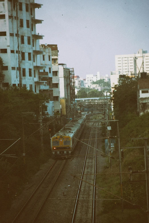 a train traveling down train tracks next to tall buildings, unsplash, old dhaka, fujifilm superia, low quality photo, bangkok