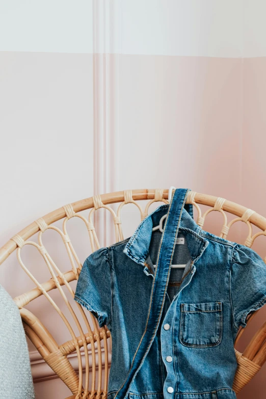 a small child's jean shirt sitting on top of a wicker chair