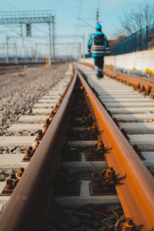 a blue fire hydrant sitting on top of a train track, a picture, by Niko Henrichon, unsplash, lone person in the distance, orange line, walking towards the camera, engineer