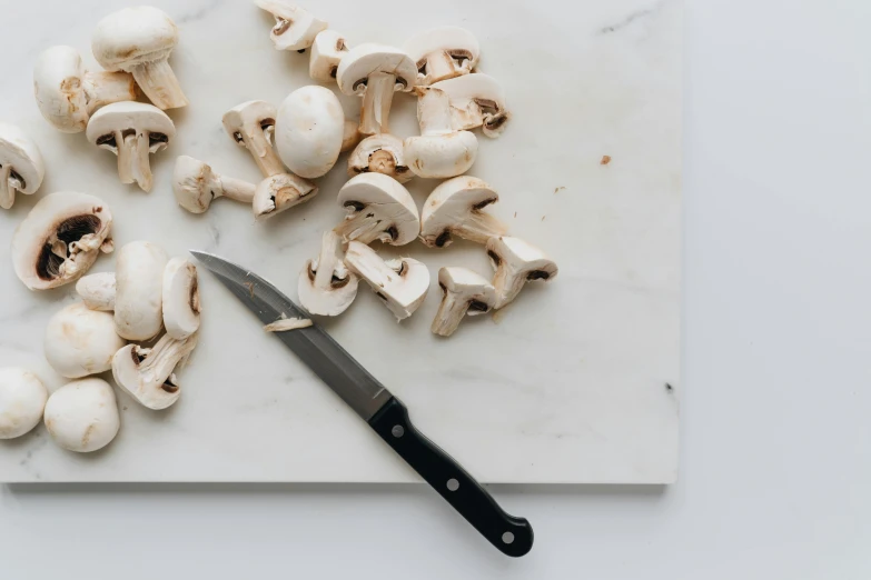 a knife sitting on top of a cutting board next to mushrooms, by Carey Morris, with a white background, white, jovana rikalo, cream of the crop