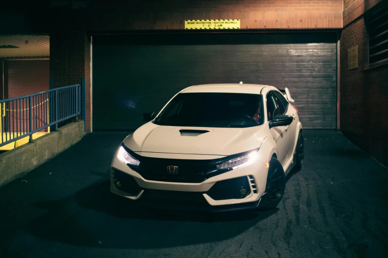 a honda civic type with its headlights on in a garage