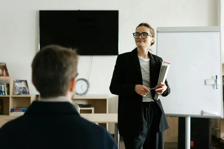 a woman standing in front of a whiteboard in a classroom, pexels contest winner, wearing a suit and glasses, speech, hip corporate, lachlan bailey