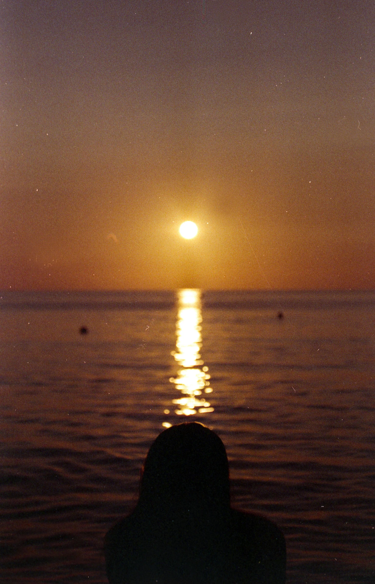 a person sitting on a beach watching the sun set, a picture, by Aguri Uchida, romanticism, 35mm!!! 1990, ibiza, alternate album cover, ((sunset))