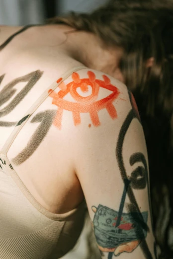 a woman with a tattoo on her arm, inspired by Taro Yamamoto, trending on pexels, graffiti, eye of providence, white and orange breastplate, lil peep, warpaint aesthetic