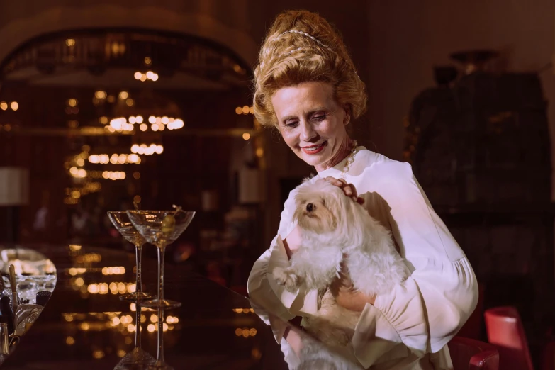 a woman is holding a white dog at a bar