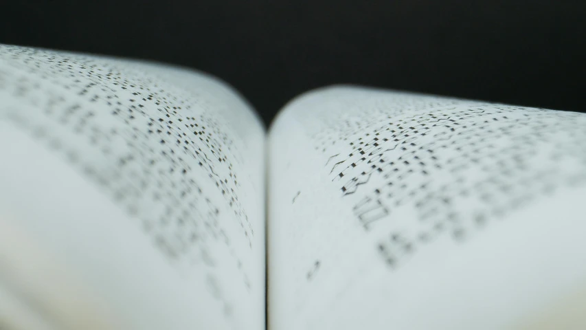 an open book sitting on top of a table, a stipple, unsplash, ascii art, middle close up, sparse freckles, multiple stories, shot from below