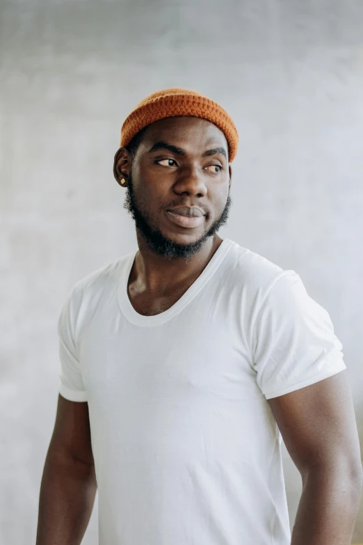 a man wearing a white t - shirt and a hat is posing