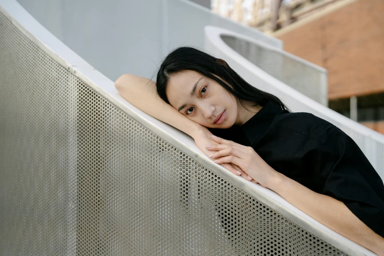 a woman sitting on top of a metal bench, inspired by Fei Danxu, pexels contest winner, long thin black hair, issey miyake, portrait image, architect