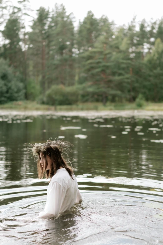 a woman in a body of water with trees in the background, by Grytė Pintukaitė, unsplash, renaissance, baptism, cottagecore hippie, boys, low quality photo