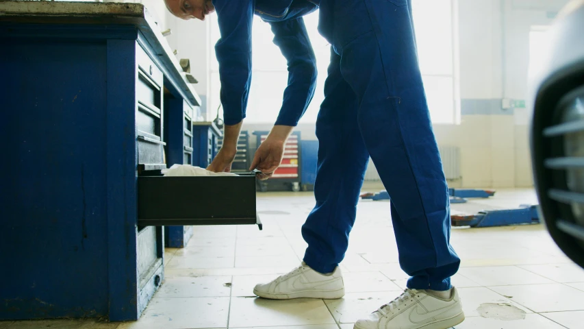 a man working on a car in a garage, pexels contest winner, shows a leg, carrying a tray, wearing plumber uniform, konica minolta