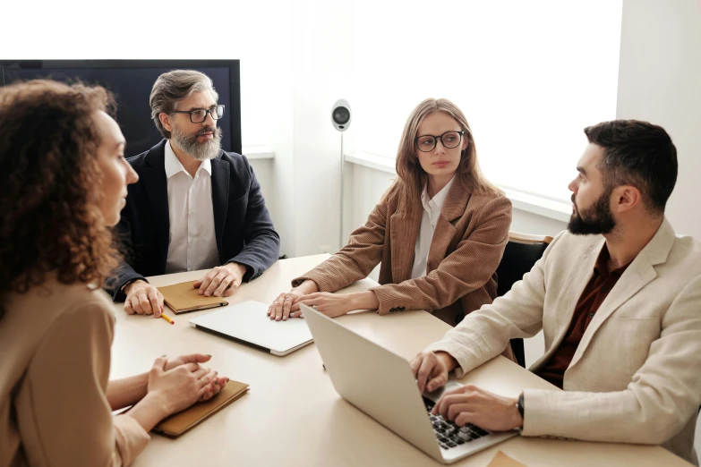 a group of people sitting around a table with laptops, by Everett Warner, trending on pexels, royal commission, wearing a suit and glasses, presentation, brown