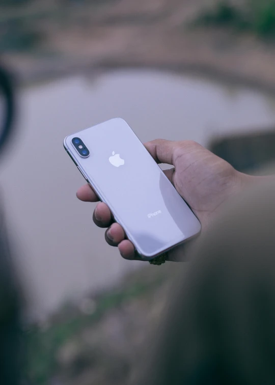 a person holding an iphone in their hand, pexels contest winner, white and silver, square, from back, ( ( theatrical ) )