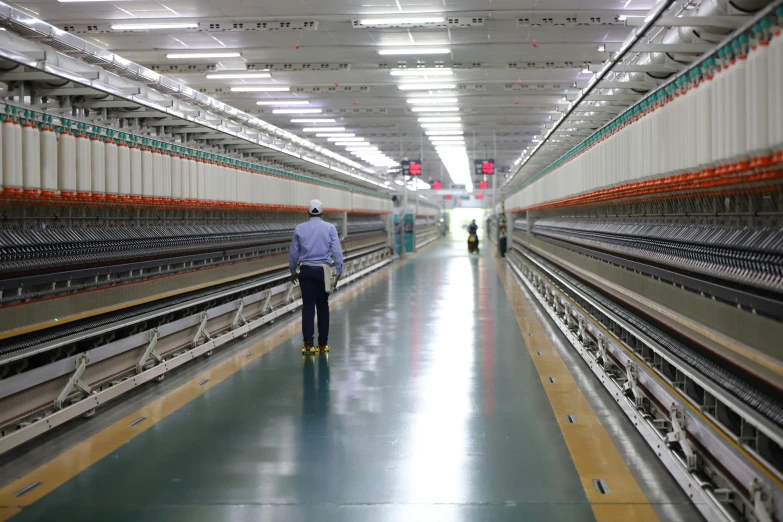 a man in blue shirt standing on aisle way next to rows of bird cages