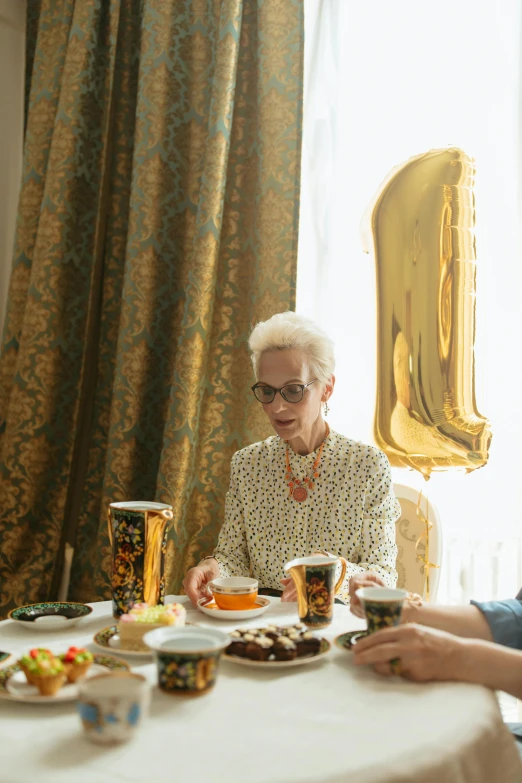 a couple of people that are sitting at a table, by Anita Malfatti, pexels contest winner, hyperrealism, at a birthday party, gold decorations, grandma, balloon