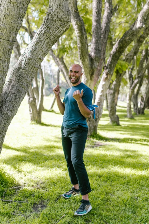 man in blue shirt standing on grass under a tree
