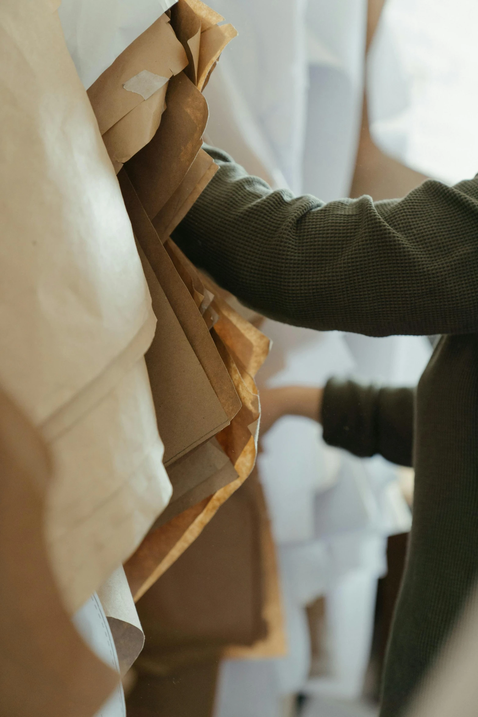 a man standing next to a pile of boxes, a marble sculpture, trending on unsplash, folds of fabric, ocher details, white sleeves, upclose