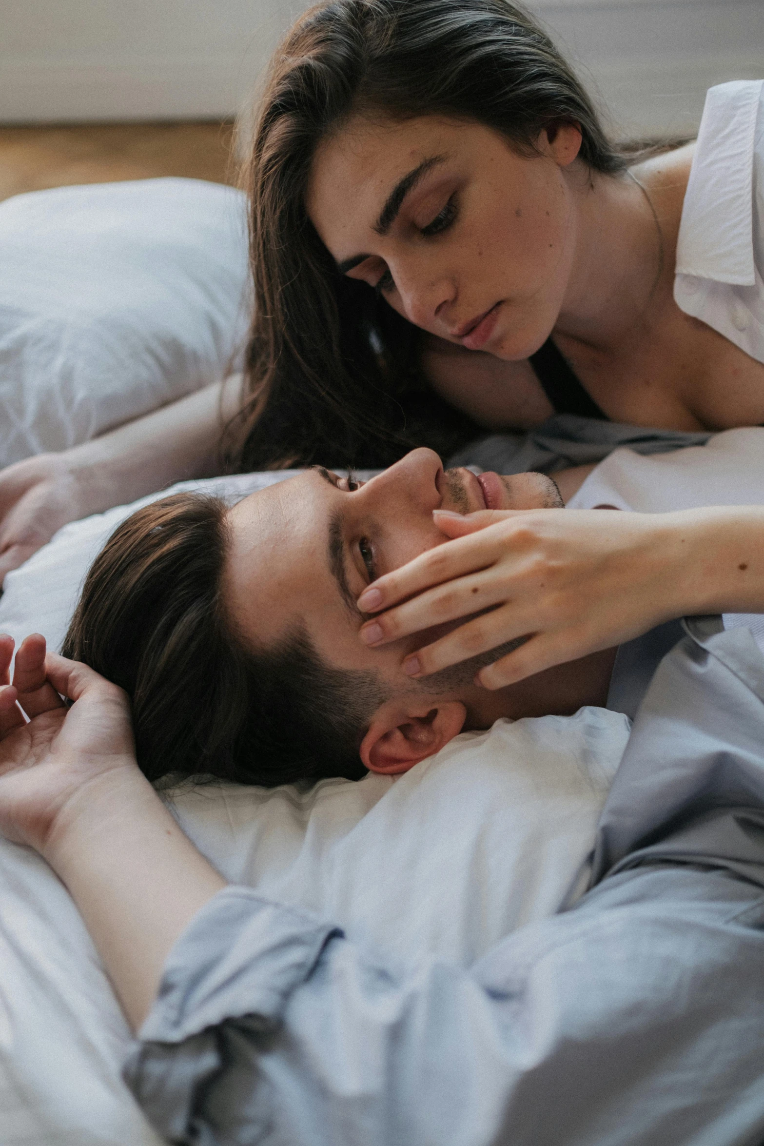 a man and woman laying in bed next to each other, inspired by Elsa Bleda, trending on pexels, hand on his cheek, sleepy fashion model face, shy looking down, ignant