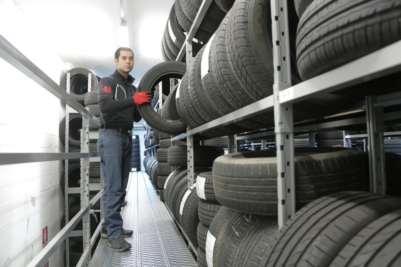 a man standing in front of a rack of tires, by Tilo Baumgärtel, hurufiyya, customer, contain, technical, highlights