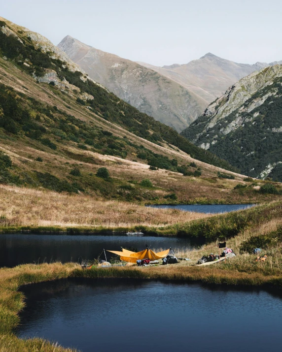 a couple of boats sitting on top of a lake, by Jessie Algie, unsplash contest winner, land art, tent, carpathian mountains, near pond, thumbnail