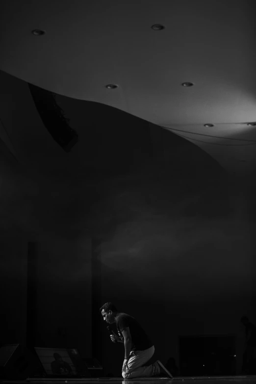 a man riding a skateboard up the side of a ramp, a black and white photo, by Joze Ciuha, unsplash contest winner, light and space, ceiling hides in the dark, sitting alone in a cafe, dramatic theater lighting, misha gordin