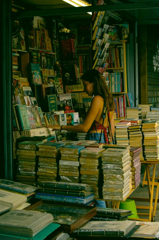 a woman standing in front of a book store, pexels contest winner, happening, piles of books, vintage color, afternoon hangout, ((oversaturated))