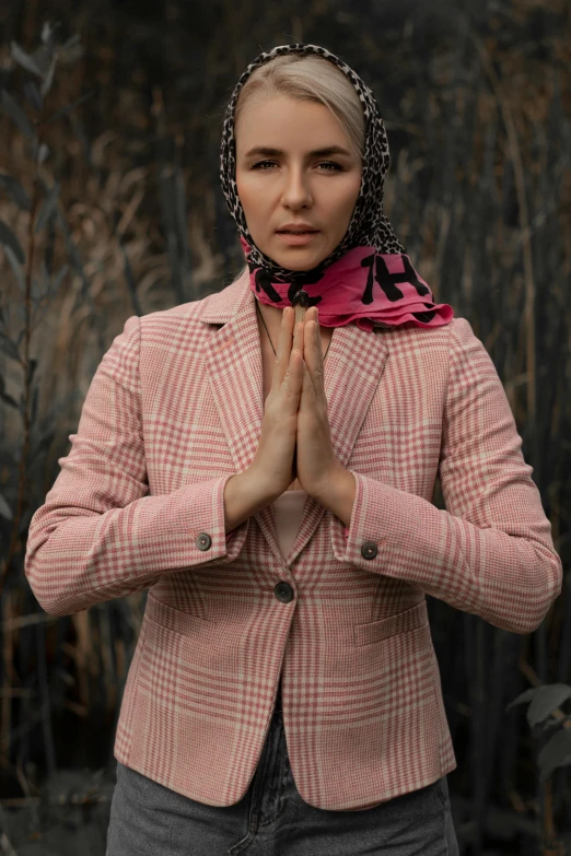 a woman standing in a field with her hands together, inspired by Nil Gleyen, wearing a light - pink suit, patterned scarf, reza afshar, anjali mudra