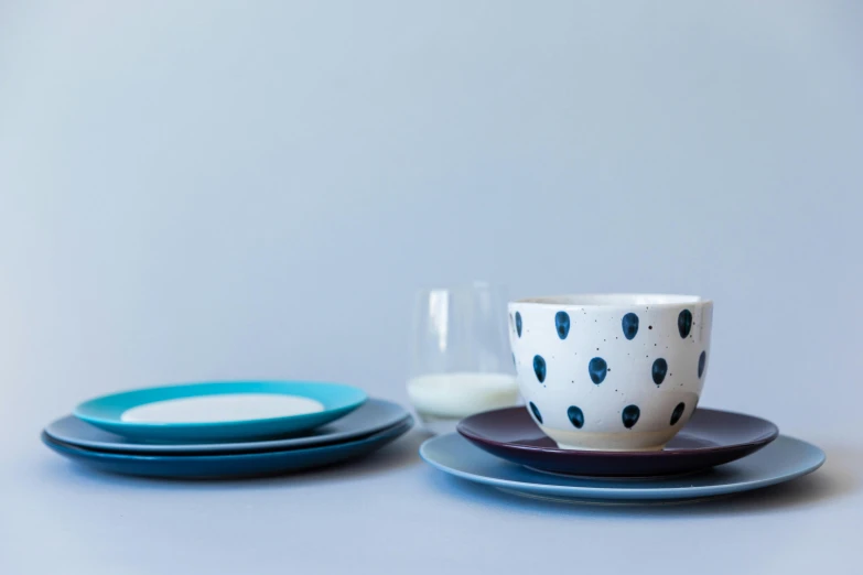 a close up of a cup and saucer on a table, a still life, inspired by Doug Ohlson, minimalism, black and blue and purple scheme, polka dot tables, teal, organic ceramic white