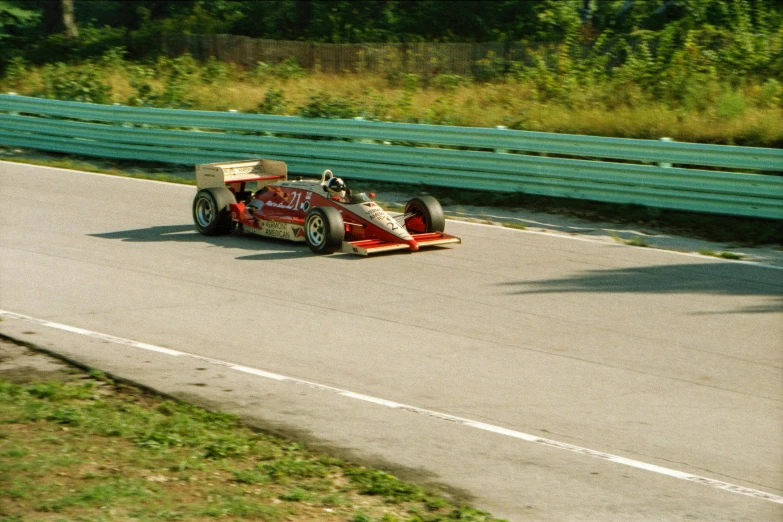 a vintage race car driving down a narrow paved road