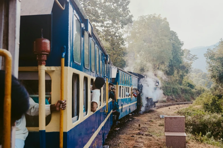 a train traveling down train tracks next to a forest, indian temple, half blue, steamy, 90s photo