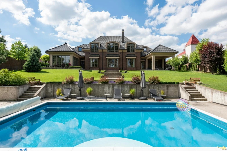 a house with a pool in front of it and steps leading up to the front lawn