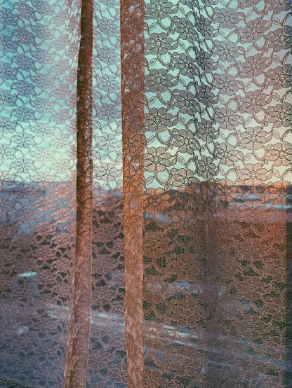 view through a mesh curtain with hills and sky in background
