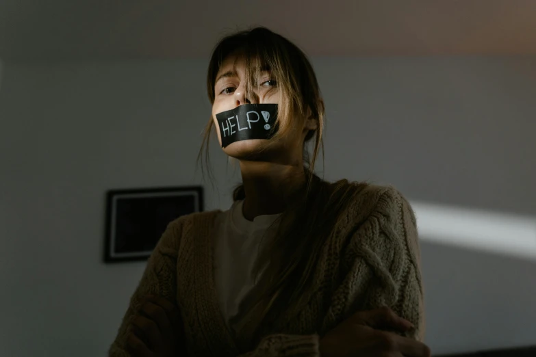 a woman in brown sweater with tape on face next to window