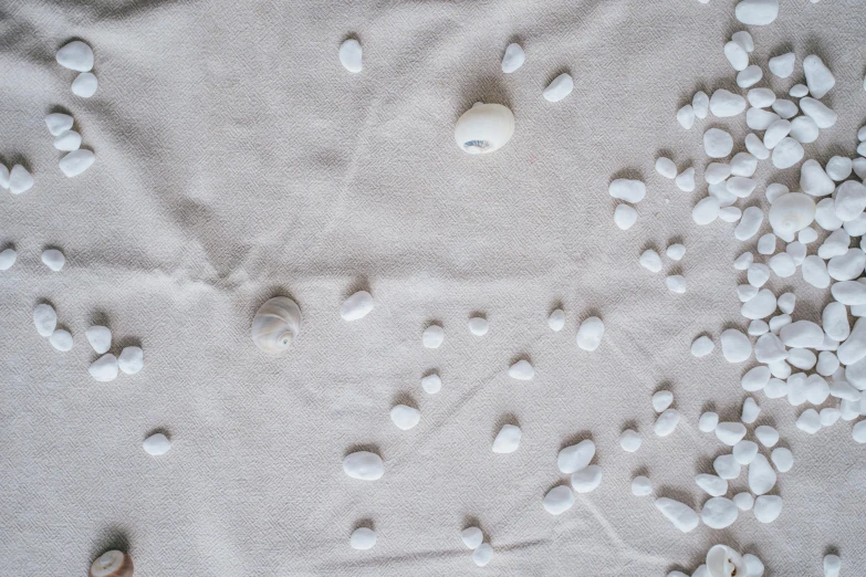 a pile of white rocks sitting on top of a bed, inspired by Vija Celmins, unsplash, plasticien, wet fabric, pearls, wide overhead shot, tablecloth