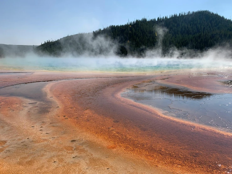 steam rises from a pool of water surrounded by a hillside