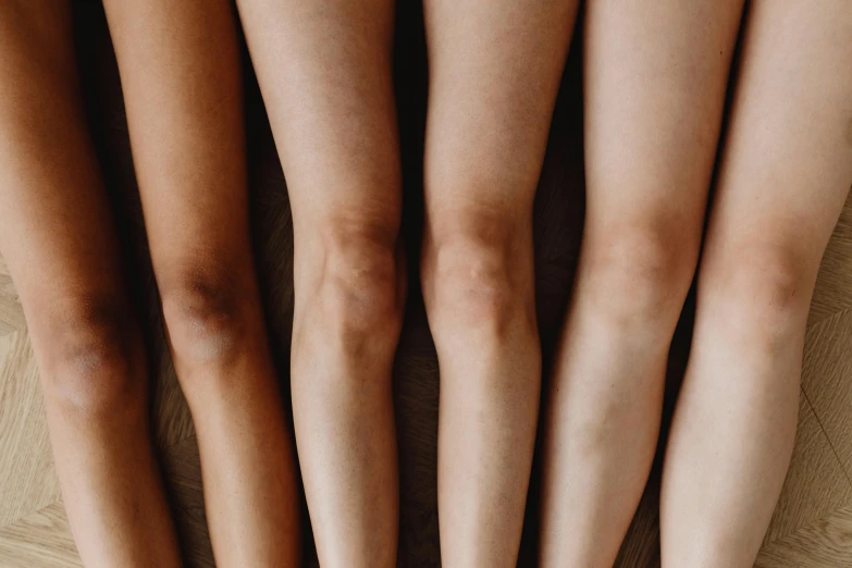 a group of women standing next to each other on a wooden floor, inspired by Vanessa Beecroft, trending on pexels, antipodeans, thighs close up, her skin is light brown, gradient brown to white, diverse