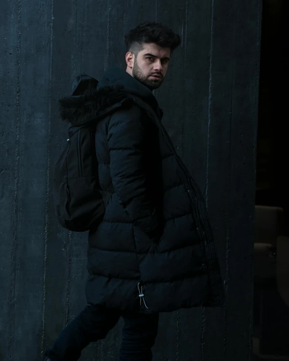 a man is wearing a jacket and scarf while standing in the dark