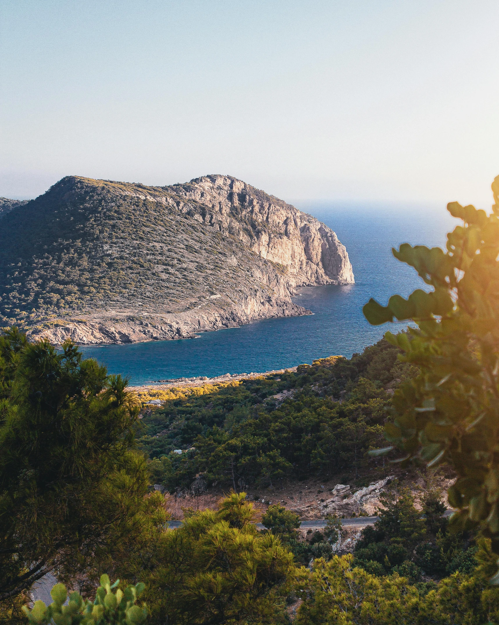 a mountain side near a body of water and some trees