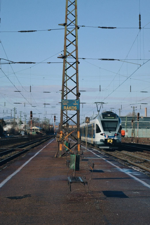 a train traveling down train tracks next to a train station, a picture, by Sven Erixson, happening, overhead wires, thumbnail, 8k octan photo