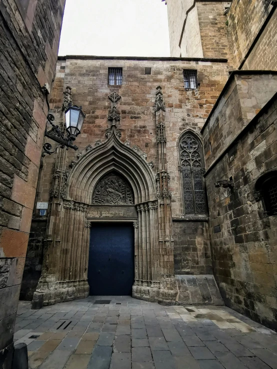 a stone building with a blue door in front of it, inspired by Modest Urgell, pexels contest winner, romanesque, gothic quarter, dark gloomy church, wide high angle view, ancient”