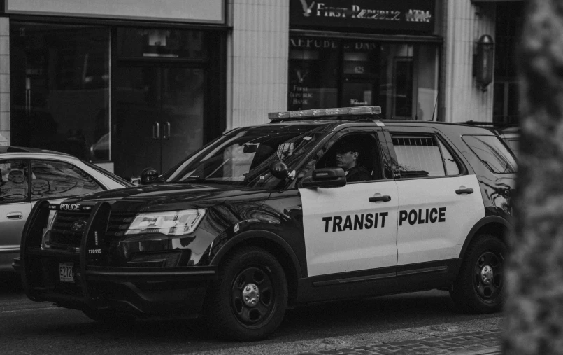 a black and white photo of a transit police car, by Carey Morris, trending on unsplash, transformer, lgbtq, featured, older male