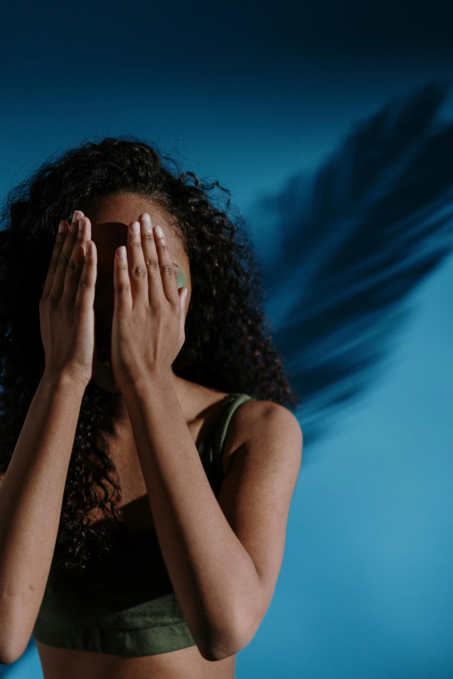 a woman covering her face with her hands, trending on pexels, renaissance, dynamic wavy hair, dramatic blue light, ashteroth, angel protecting woman