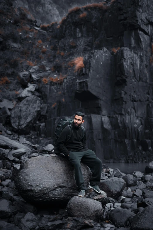 a man sitting on rocks in front of a mountain